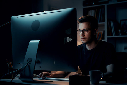 Graphic designer editing photos on a bright monitor in a dark room